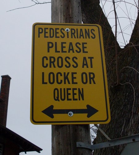 Posted sign at Aberdeen and Kent: 'PEDESTRIANS PLEASE CROSS AT LOCKE OR QUEEN'