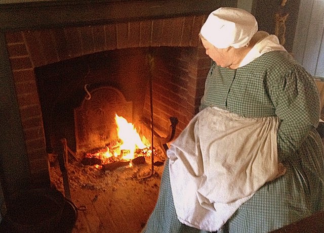 A log cabin mistress tends a warming fire.