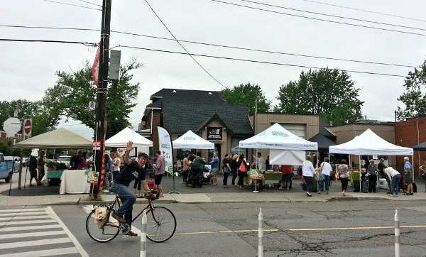 Local urban farmer Russ Ohrt waves from a bicycle in front of the Locke Street Farmers' Market (RTH file photo)