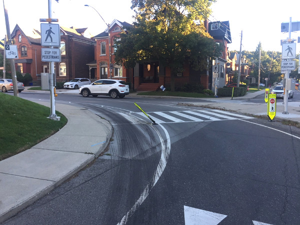 Damaged knockdown placard and motor vehicle tire marks in the bike lane at Queen and Herkimer