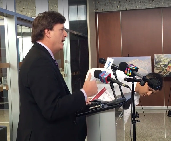 Green (right) looks at the official 'Hamilton City Hall' podium while Whitehead speaks (Image Credit: Screen capture, video by CBC Hamilton)