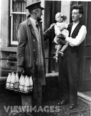 Circa 1935: A milkman chats with a father holding a baby, as he leaves the daily quota of milk on the doorstep. (Photo by Fox Photos/Getty Images)