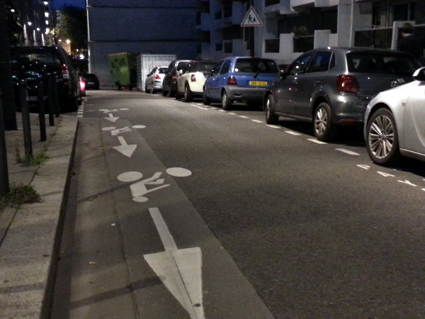 Left-side contraflow bike lane with cars parked on right side