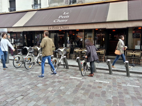 Woman locking a Vélib' rental bike on a pedestrian street in the Latin Quarter