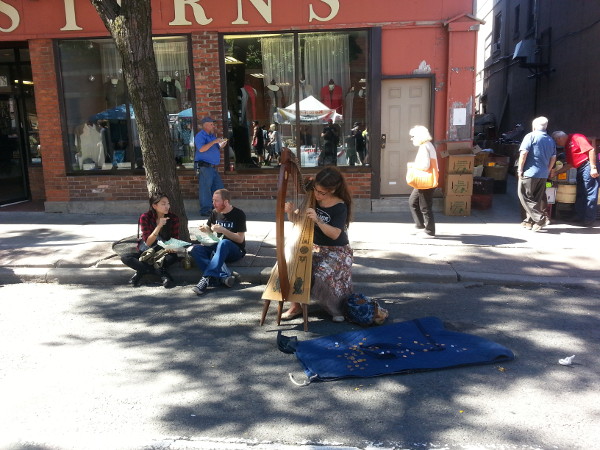 A harpist performed in a spot of shade